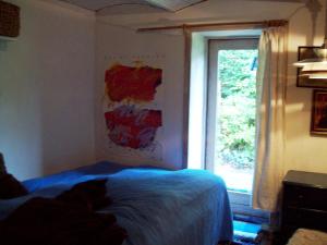 un gato acostado en una cama en un dormitorio con ventana en Ingridsboplads, en Vildbjerg