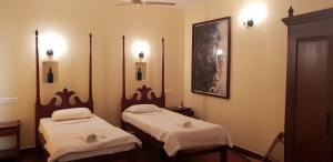 2 camas individuales en una habitación con luces encendidas en Raintree Lodge, en Kochi