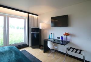 een slaapkamer met een bed, een bureau en een raam bij BG Hotel by WMM Hotels in Bad Grönenbach