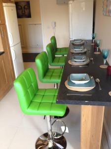 une salle à manger avec des chaises vertes et une table dans l'établissement Trigg Hall, à Bradford