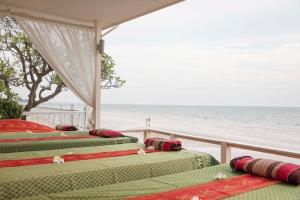 3 Betten auf einem Balkon mit Meerblick im Hintergrund in der Unterkunft Chom View Hotel, Hua Hin in Hua Hin