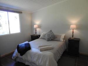 1 dormitorio con 1 cama con 2 lámparas y una ventana en Natures Way Bushbuck Cottage, en The Crags