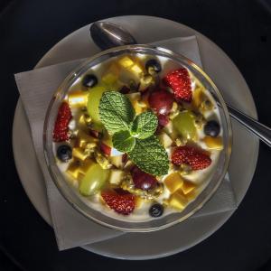 a bowl of fruit salad on a plate with a spoon at Natures Way Bushbuck Cottage in The Crags