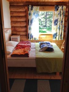 1 cama en una cabaña de madera con ventana en Olosloisto Lomat en Muonio