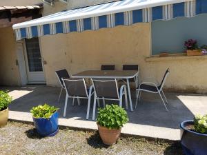 einen Tisch und Stühle auf einer Terrasse mit Pflanzen in der Unterkunft Propriété St Jean in Lazer