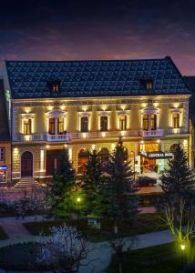 un grand bâtiment avec des lumières allumées la nuit dans l'établissement Hotel Central Park Sighisoara, à Sighişoara