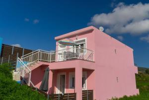 a pink house with an umbrella on the balcony at Mirage by The Sea in Alykes
