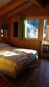 ein großes Bett in einem Zimmer mit Fenster in der Unterkunft Chalet Edi in Münster VS