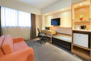 a hotel room with a couch and a desk and a television at Green Garden Apartments-A in Taipei