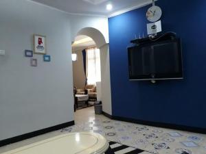 a room with a blue wall with a tv on the wall at Cihampelas Homestay in Bandung