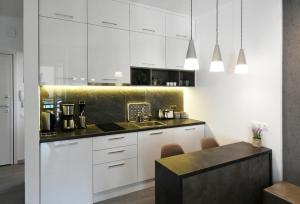 uma cozinha com armários brancos e um balcão preto em Nest Apartment em Atenas