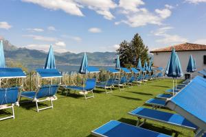 een rij blauwe stoelen en parasols op een gazon bij Hotel Internazionale in Torri del Benaco