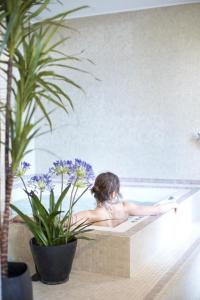 a woman sitting in a bath tub next to a vase of flowers at Fourvière Hôtel in Lyon
