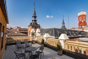 Un balcón con mesas y sillas en un edificio en Plaza Mayor Suites & Apartments, en Madrid