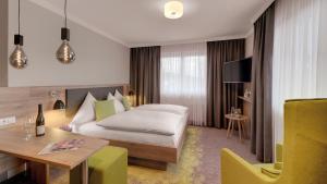 une chambre d'hôtel avec un lit et une table dans l'établissement Pfalzhotel Asselheim, à Asselheim