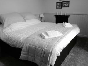 a black and white photo of a bed with towels on it at Crown and Anchor in Dundrennan