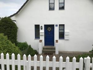 グロヴェにあるFerienwohnung Lillyの青い扉と柵の白い家