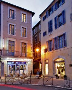 un groupe de bâtiments avec des tables et des chaises dans une rue dans l'établissement Hôtel Le Coin des Halles, à Cahors