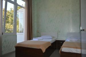 two beds in a room with a window at hotel niks in Makhinjauri