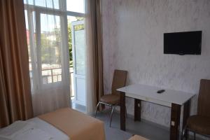 a room with a bed and a desk and a television at hotel niks in Makhinjauri