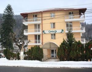 un gran edificio amarillo con sombrilla en la nieve en Pensiunea Confort, en Buşteni