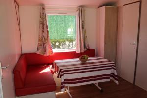 a red chair and a table in a room with a window at Camping Playa Arenillas in Islares