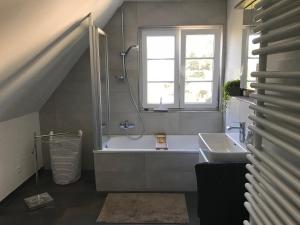 La salle de bains est pourvue d'une baignoire, d'un lavabo et d'une fenêtre. dans l'établissement Ferienwohnung Haltingen, à Weil am Rhein