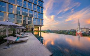 uma piscina com cadeiras e um guarda-sol ao lado de um edifício em Pan Pacific Yangon em Yangon