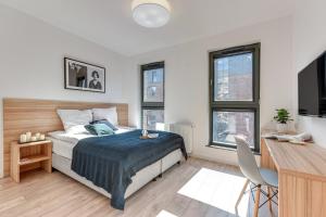 a bedroom with a bed and a desk and windows at Browar Gdanski Budget by Renters in Gdańsk