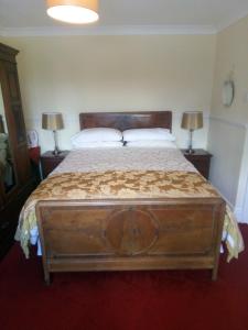 a bedroom with a large wooden bed with two lamps at Fuchsia House Bed and Breakfast Connemara in Renvyle