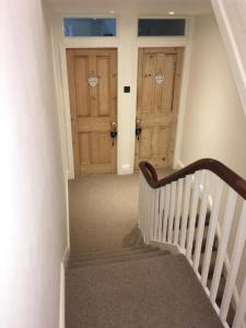 a staircase with two wooden doors in a house at Raymonds in Douglas