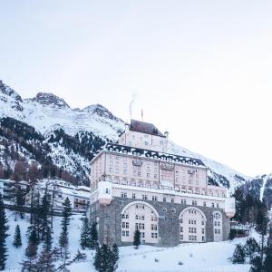 um grande edifício na neve em frente a uma montanha em Schloss Hotel & Spa Pontresina em Pontresina