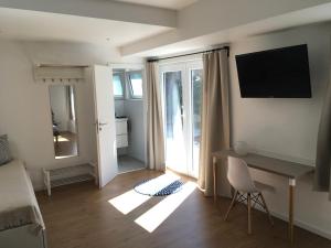 a living room with a desk and a television on the wall at Alte Schmiede in Weisweil