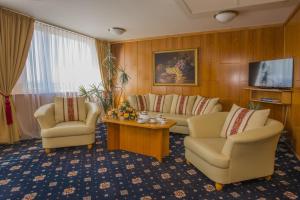 a living room with two chairs and a couch and a tv at TOP HOTEL Praha in Prague