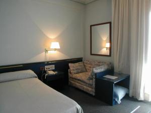 a hotel room with a bed and a chair at Hotel Rey Sancho Ramírez in Barbastro