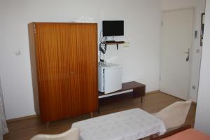 a living room with a wooden cabinet and a tv at Sobe Stipe in Primošten
