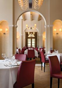 ein Esszimmer mit weißen Tischen und roten Stühlen in der Unterkunft Schloss Hotel & Spa Pontresina in Pontresina