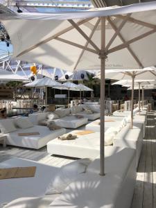 eine Reihe weißer Betten mit Sonnenschirmen und Tischen in der Unterkunft Elit 2 Apartment in Sonnenstrand