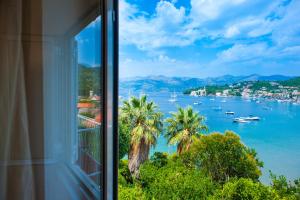 una ventana con vistas a una bahía con palmeras y barcos en Pansion Tereza en Lopud