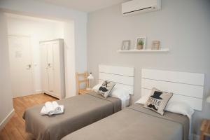 2 Betten in einem Zimmer mit weißen Wänden und Holzböden in der Unterkunft Hotel Smile & Co Hostal Boutique in Alicante