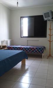 Habitación con cama, ventana y TV. en Apartamento Guilhermina - Ed Frente ao Mar, en Praia Grande