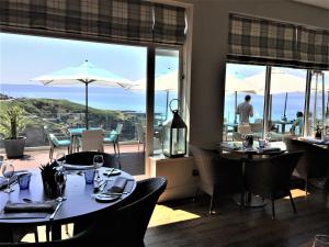 a restaurant with tables and chairs with a view of the ocean at Watersmeet Hotel in Woolacombe