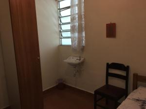 a small bathroom with a sink and a window at Hotel Chaves - Quartos Individuais in Sao Paulo