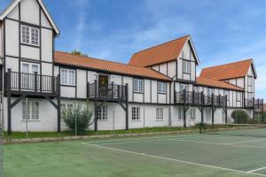 a building with a tennis court in front of it at 4 Bell Lodge, Thorpeness in Thorpeness