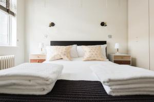 1 dormitorio con 1 cama grande con sábanas y almohadas blancas en The Oxford Street Studio - 1BDR in Paddington, en Londres