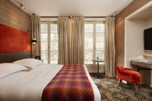 een slaapkamer met een groot bed en een rode stoel bij Le Pavillon des Lettres in Parijs