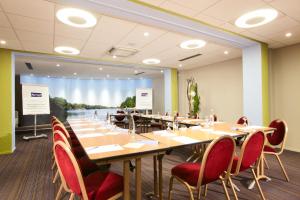 Kyriad Hotel Nevers Centre في نيفير: قاعة المؤتمرات مع طاولة وكراسي طويلة