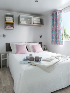 a bedroom with a white bed with pink pillows at Strandcamping Gruber in Faak am See