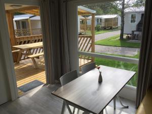 a dining room with a table and a view of a deck at Strandcamping Gruber in Faak am See