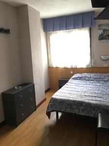 a bedroom with a bed and a dresser and a window at Hostal Hilton in Burgos